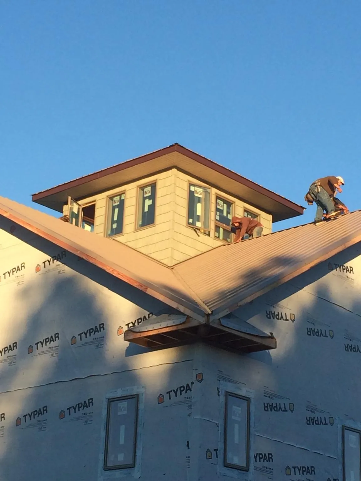 Roofers working around a rooftop cupola on a new metal roof at sunset — Roof Waterproofing in Caledonia by Roofing Brothers